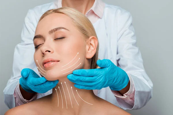 Doctor examining a patient's neck and face with blue gloves on a gray background