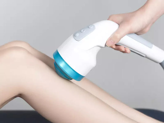 Person using a handheld shockwave device on their leg against a gray background